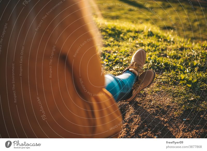 Woman relaxing at sunset woman yellow coat autumn winter copy space unrecognizable boots grass feet relaxation hiking tourism tourist young rest morning dawn