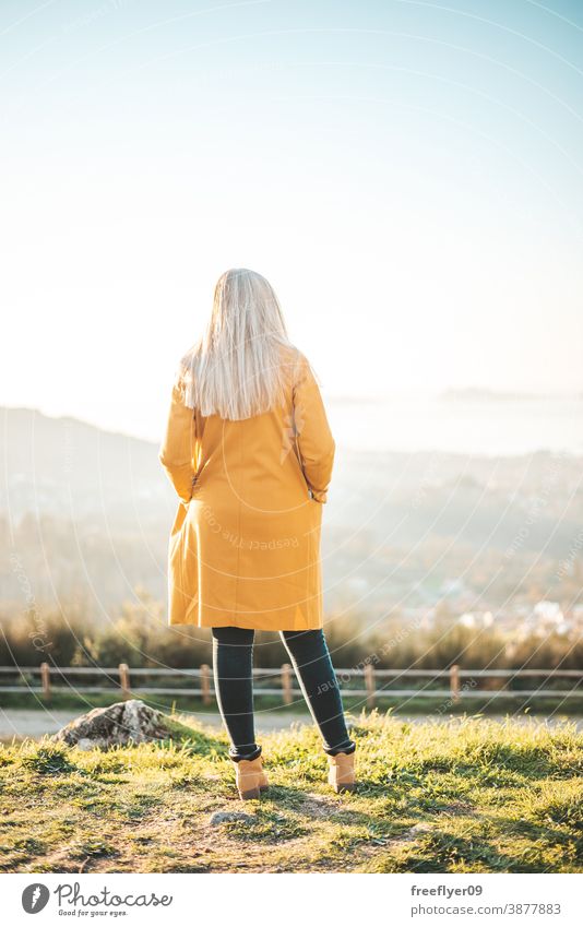 Woman on a yellow coat sitting on a bench contemplating the landscape woman winter autumn vigo galicia nature outdoors freedom sunset contemplation sky coolness