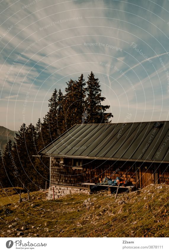 Hiker lying on a bench of a mountain hut to sunbathe sharpened Hiking autumn colours Autumn outtdoor Trip hiking tour Mountain Alps Bavaria Sky Blue variegated