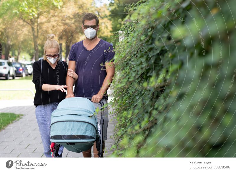 Worried young parent walking on empty street with stroller wearing medical masks to protect them from corona virus. Social distancing life during corona virus pandemic