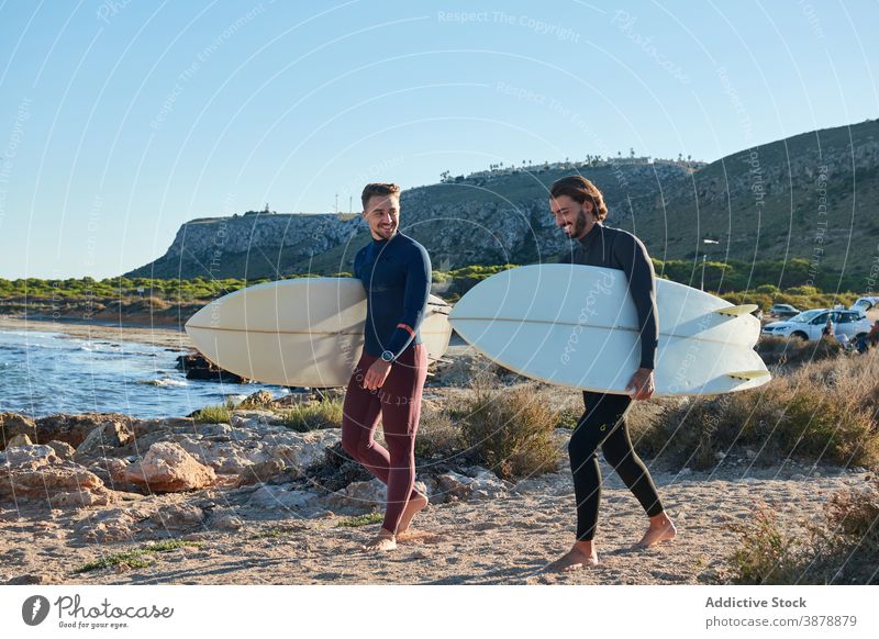 Men with surfboards walking along beach surfer men sea sunset male friend friendship seashore nature wet summer seaside water coast cheerful coastline guy