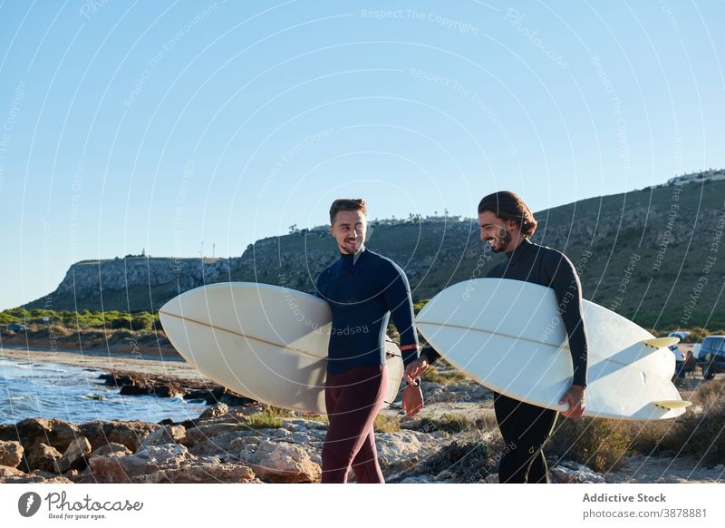 Men with surfboards walking along beach surfer men sea sunset male friend friendship seashore nature wet summer seaside water coast cheerful coastline guy