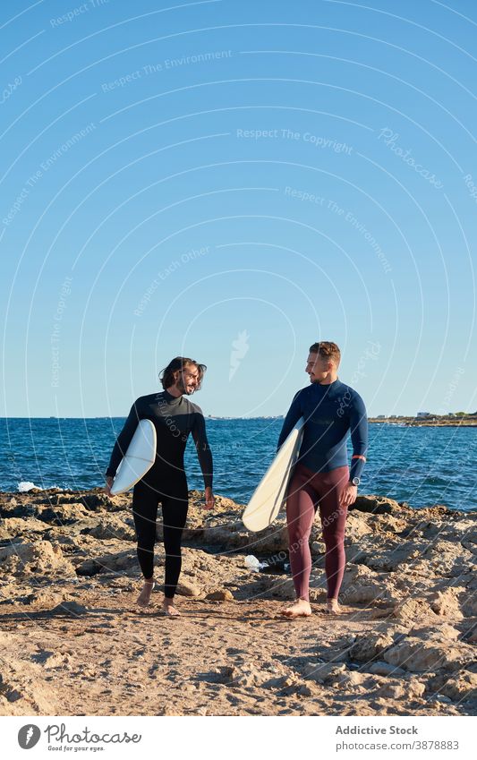 Men with surfboards walking along beach surfer men sea sunset male friend friendship seashore nature wet summer seaside water coast cheerful coastline guy