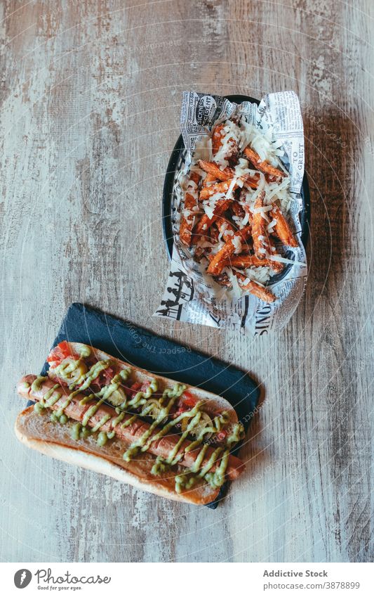 Appetizing hotdog and French fries on table in cafe fast food hot dog junk food french fries potato serve unhealthy delicious fresh spicy sauce tasty yummy