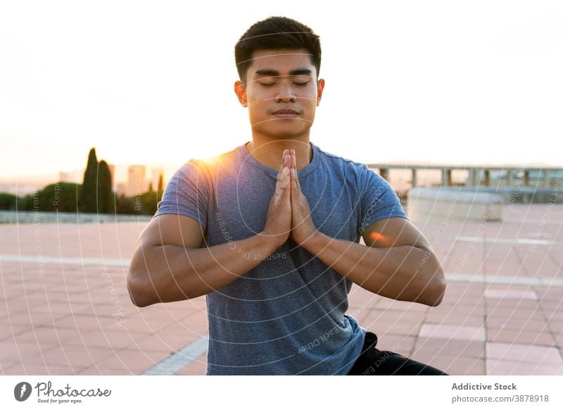 Content man meditating in Tree pose at sundown meditate yoga balance stress relief mindfulness tree pose namaste eyes closed asana male ethnic asian sunset sky