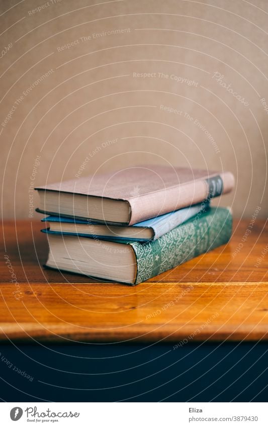 Three books lie stacked on a wooden chest of drawers Wood Education Literature Chest of drawers Book Reading matter Old Novel Stack pile of books