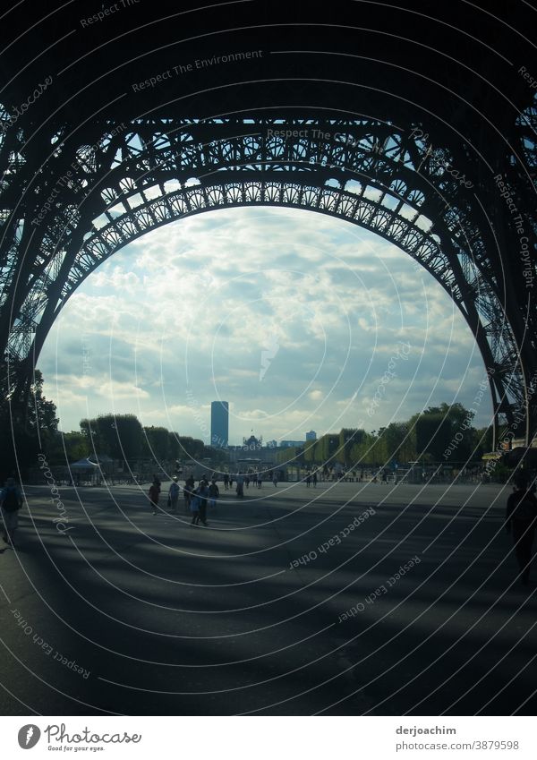 Under the Eiffel Tower .  With light and shadow . Above me the Great Steel Frame . In the background a skyscraper and many trees. Architecture Sky Building