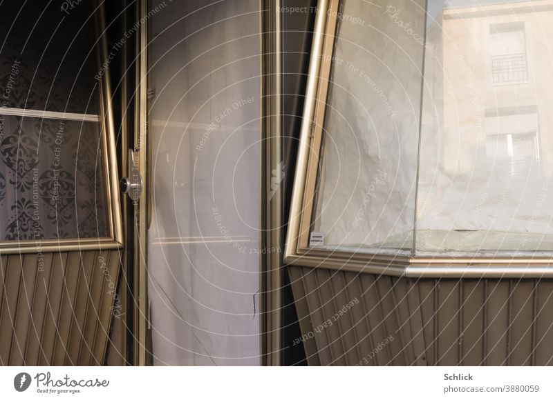 Part of a facade of an old closed shop from the 60s with shop window and door in gold-coloured aluminium and notice protection electronique business Closed