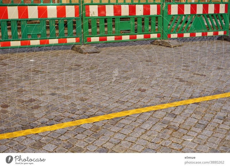 green barrier beacons with red and white stripes at the roadside and a yellow barrier on the paved road / road narrowing / construction site Barrier beacons