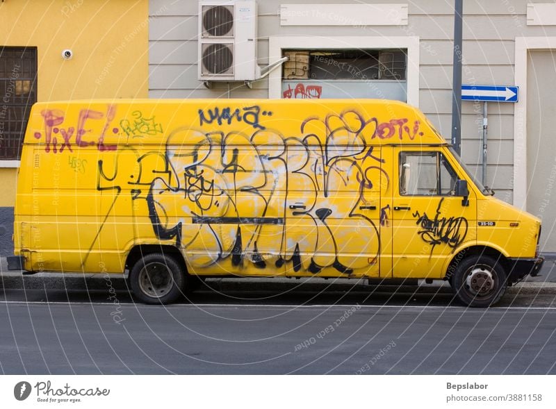 Yellow van covered with graffiti tag in the Milan street pick up yellow asphalt auto back background big blank business car cargo carrier container country