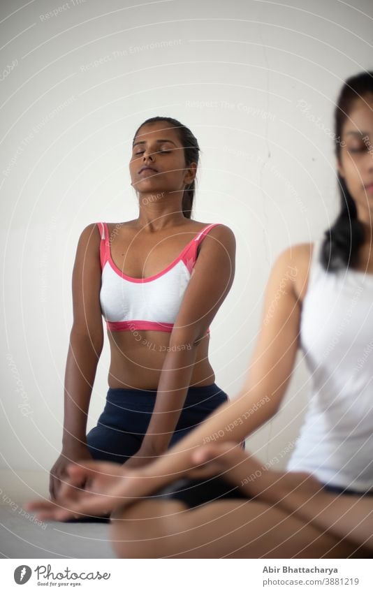 Indian black and white brunettes girls performing yoga/sports /exercise in underwear in front of a white background. Indian lifestyle adult asian attractive