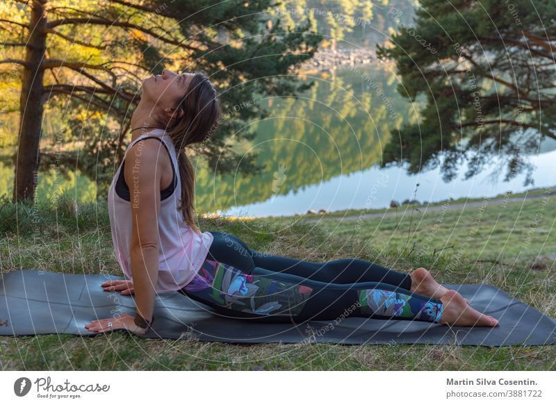 Woman practices yoga alone in the forest Back view Outdoor activity Young attractive woman practicing yoga, exercising exercising working out Women is meditating alone at sunrise.