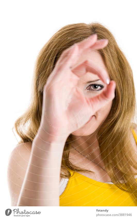 Looking through the ok sign Frau jung kaukasisch Blick in die Kamera weißer Hintergrund isoliert Auge Augenblick Handzeichen O.K.-Zeichen Fokus Gesicht verdeckt