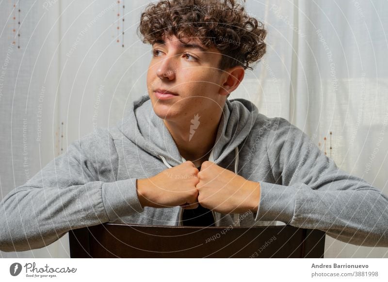 Attractive young man with curly hair wearing gray sweatshirt posing on white curtains background cheerful casual smile male adult handsome happy attractive