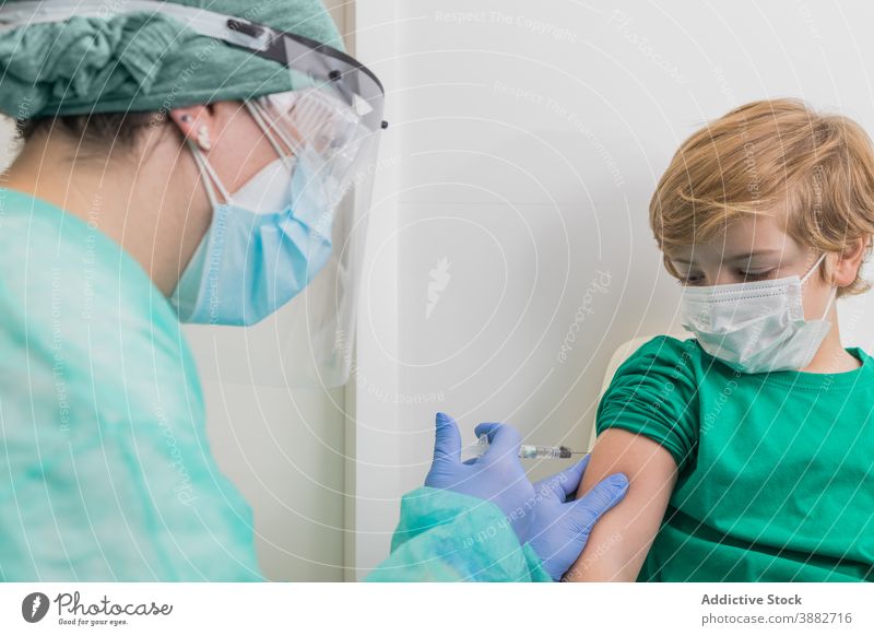 Doctor giving injection for kid in mask in hospital vaccine coronavirus syringe doctor child prevent covid 19 sterile health care medical professional