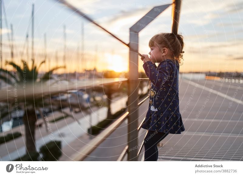 Little girl standing on bridge at sunset kid curious railing little observe urban summer evening child lifestyle childhood street female cute adorable pensive