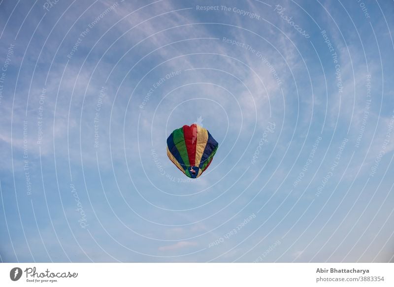 A colorful lantern/balloon is flying in the blue sky with white clouds in the afternoon of Diwali. Indian festival adventure air asia background beautiful