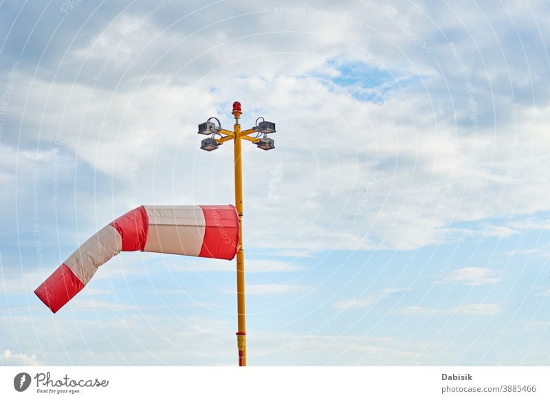 Windsock. Indicator of a blowing wind against cloudy sky windsock direction weather meteorology cone airport sign warning flag blue indicator white speed windy