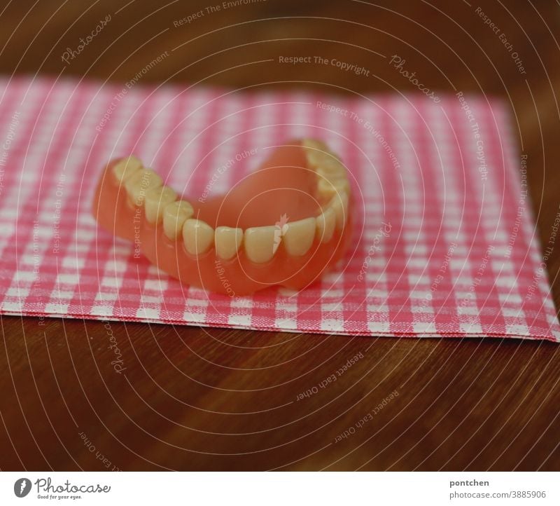 One set of teeth lies on a checkered surface. Humor, bizarre. Dental Health Set of teeth Dentist dental health senior citizens age Dental implant Teeth