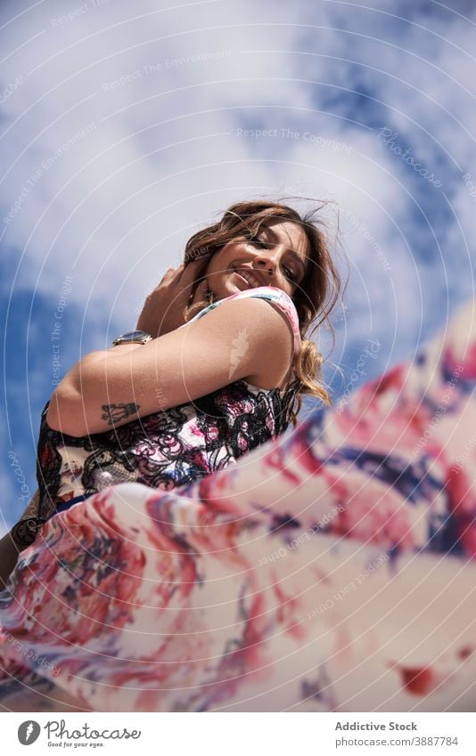 Smiling woman looking away against blue sky smile dress elegant wavy hair long hair appearance charming gentle female relax happy young style fashion cheerful