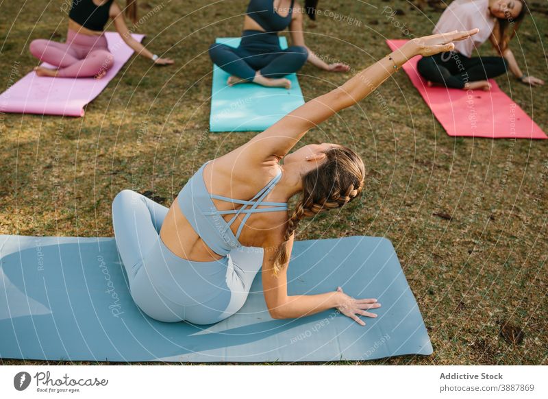 Yoga instructor doing seated side bend pose yoga women sukhasana park practice group female wellness lifestyle harmony wellbeing zen health care position