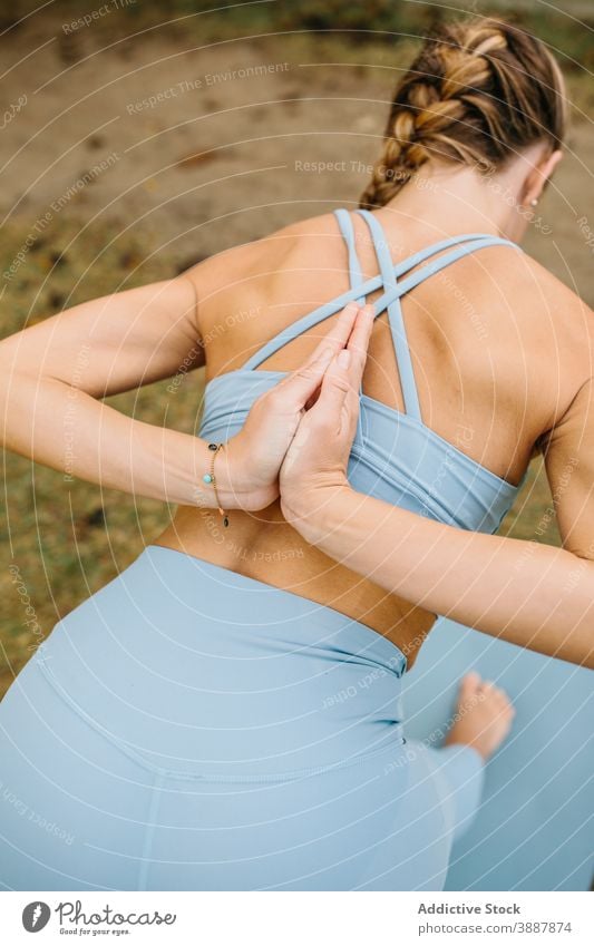 Woman doing yoga pose with prayer hands behind back woman park bound revolved crescent lunge half pyramid ardha parsvottanasana namaste stand stretch bend twist