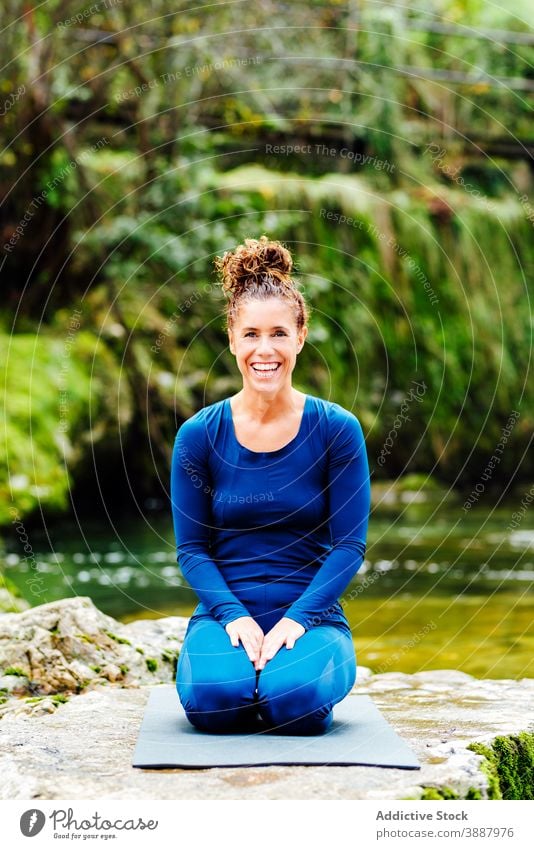 Delighted woman doing yoga in Thunderbolt asana thunderbolt  pose relax lake nature flexible vajrasana female zen practice sit happy wellness smile young