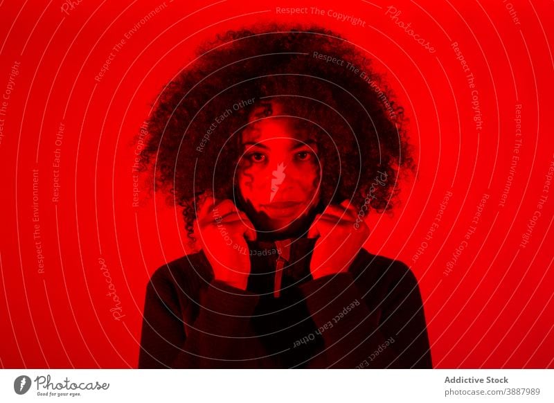 Curly haired ethnic woman in red neon illumination curly hair young illuminate light color portrait trendy female african american black appearance millennial