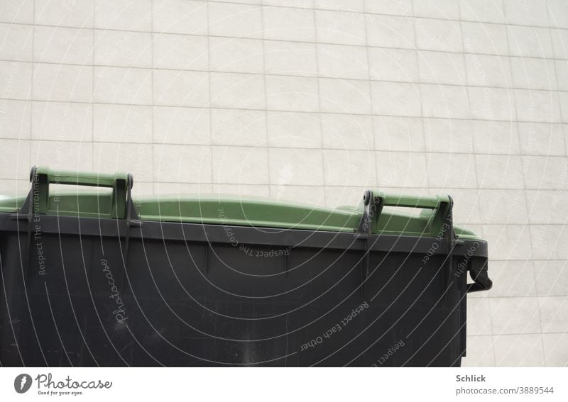 Detail of waste container with green plastic lid in front of a light-coloured facade with rectangular panels Trash container Large detail Plastic Facade