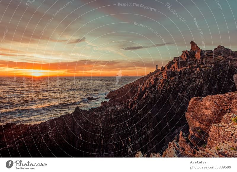 A dramatic horizontal shot of a white lighthouse during the sunset from the rocks of the coast color image architecture ocean photography tourism outdoors sea