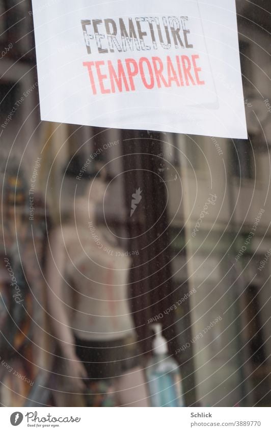 Covid-19 pandemic Shop window of a temporarily closed shop with sign in French Mannequin and bottle of hand disinfectant covid-19 business Closed