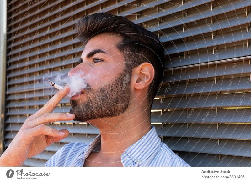 Tranquil man smoking on street smoke cigarette addict handsome city thoughtful vapor fume male building contemplate nicotine urban think relax wistful ponder