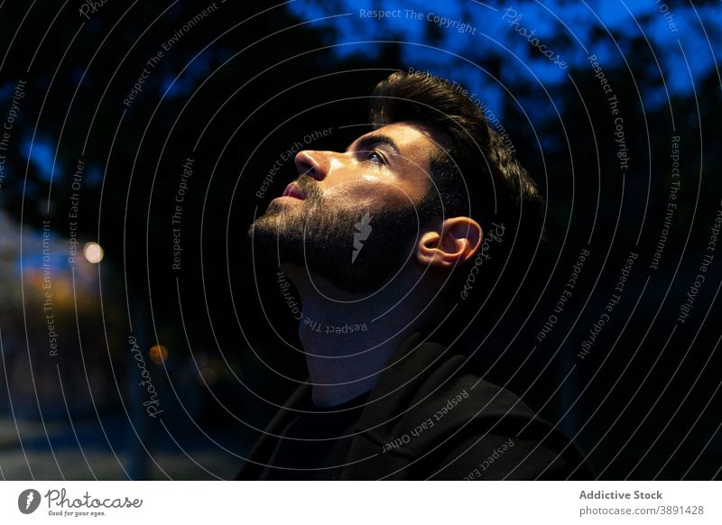 Tranquil man standing in city at night thoughtful beard appearance tranquil serene contemplate dark male casual young urban pensive style serious think unshaven