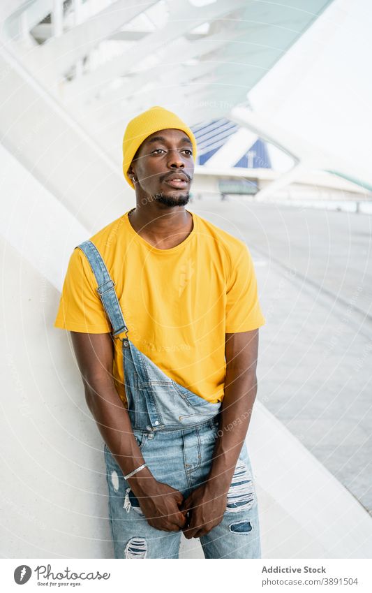 Black man standing in the street looking at camera trendy male ethnic black african american yellow outfit style modern bright appearance garment urban young