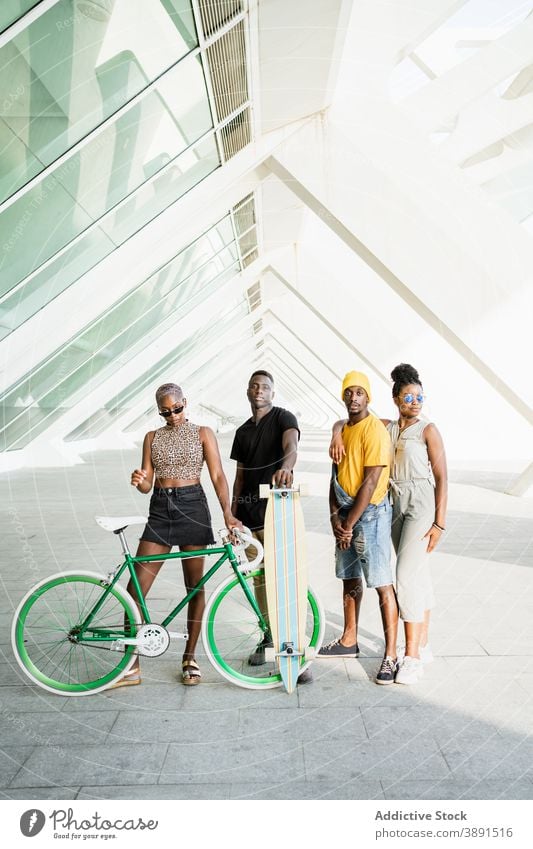 Company of cheerful friends with bike and longboard in city company hipster unity cool style bicycle generation together ethnic black african american people