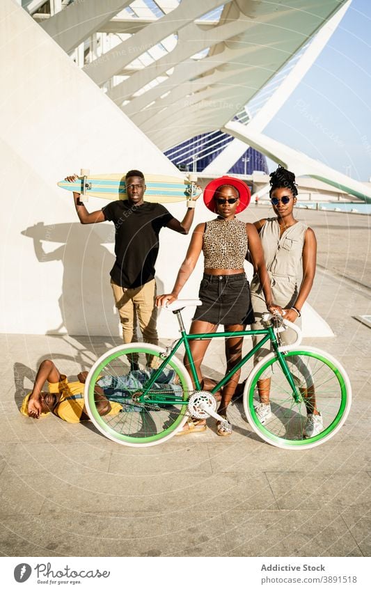 Company of cheerful friends with bike and longboard in city company hipster unity cool style bicycle generation together ethnic black african american people