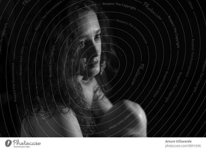 black and white young woman sitting holding her knees with black background abused headache depression afraid people cry health emotional pain stress violence