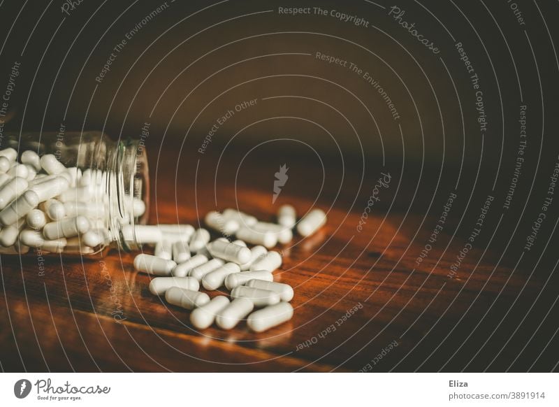 A glass from which many white medicine capsules are poured onto a table Medication pills Drug Capsules White Many Pill Pharmaceuticals Meidkament tablets Bird