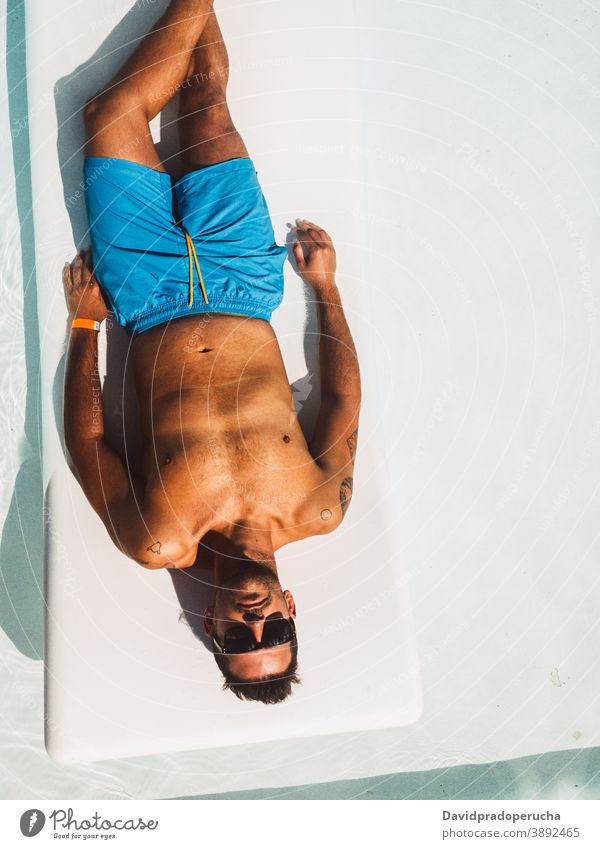 Man relaxing on deckchair at poolside sunbath lounger traveler lying vacation resort rest carefree summer hotel journey chill swimwear tourist shorts tourism