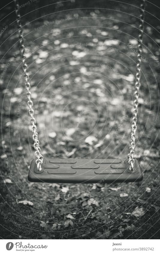 Abandoned swing on a playground in black and white | gloomy atmosphere Swing To swing Playground forsake sb./sth. foliage Deserted Autumn children's playground