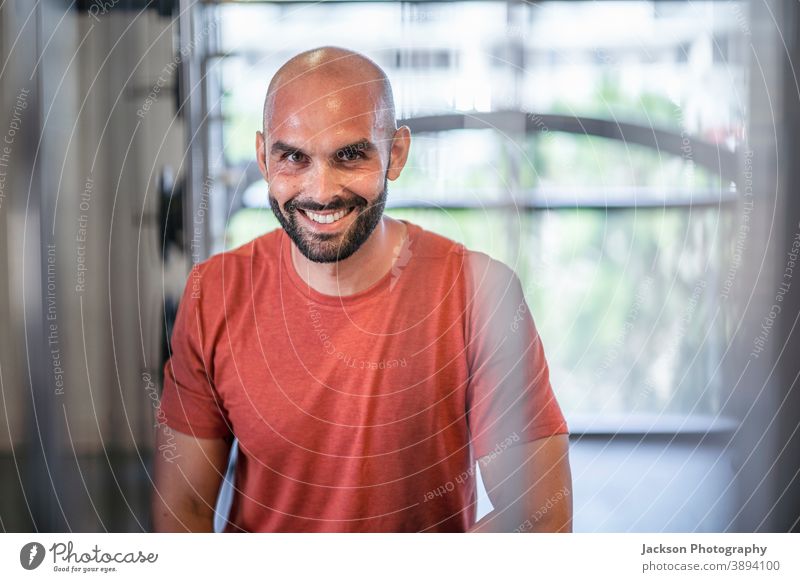 Sweaty man resting between workouts at the gym sportsman sweaty building train smile looking activity sitting bottle tired trainer break indoors equipment