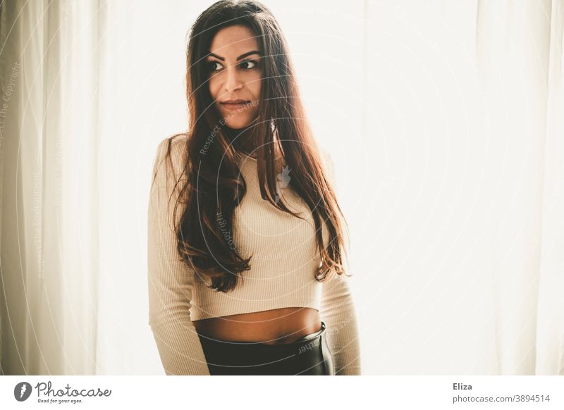 Young southern woman with long brown hair looks to the side. Back light. Woman Southern brown-haired View to the side Upper body Skeptical portrait long hairs