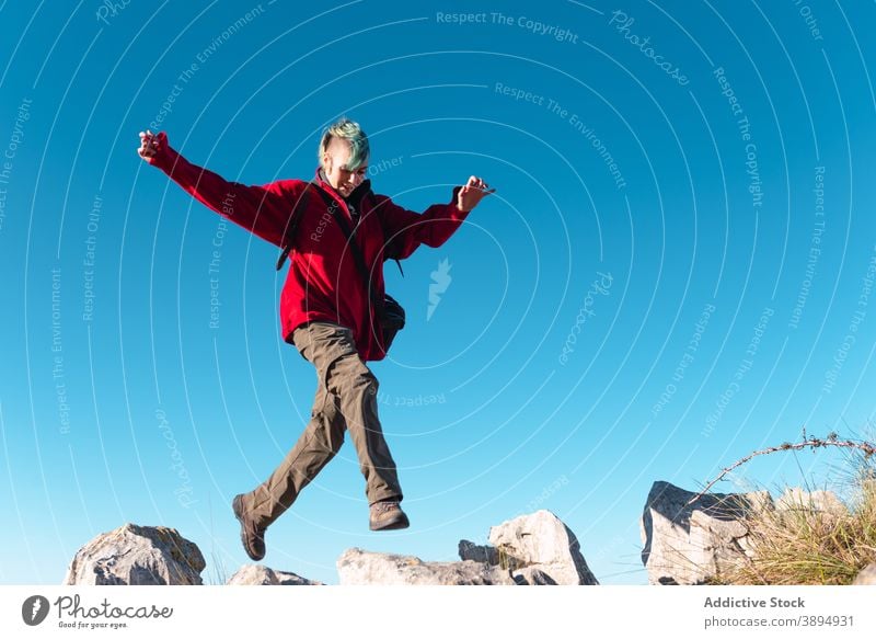 Cheerful hiker during trekking in mountains highland jump extreme adrenalin trail rock energy el mazuco asturias spain travel freedom terrain blue sky