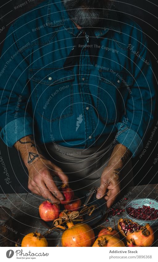 Crop person arranging ripe pomegranates on table arrange fruit pile harvest delicious rustic dark room vitamin food raw heap natural healthy organic nutrition