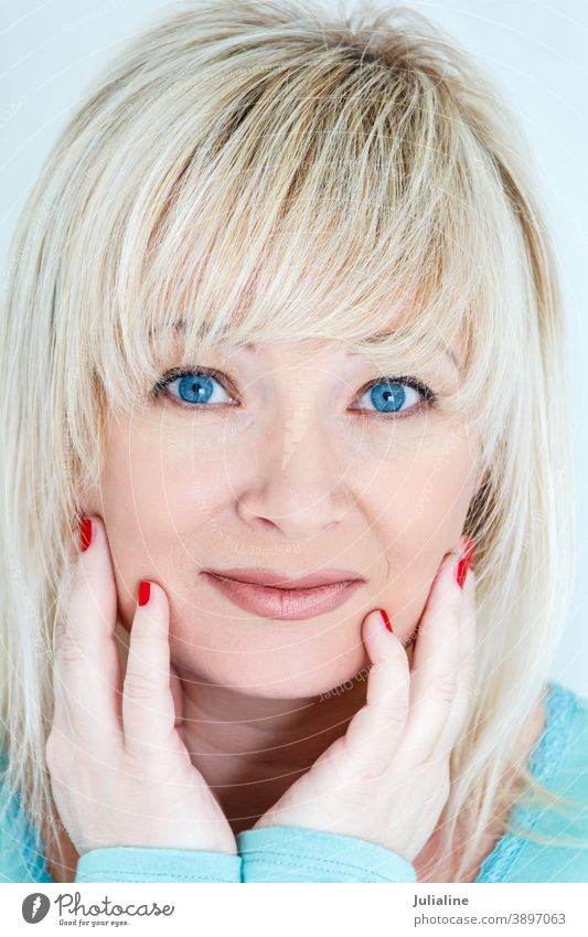 Blond woman with sapphirine eyes caucasian european female lady white blond forty empty room stool one long turquoise blue smile straight smooth expression