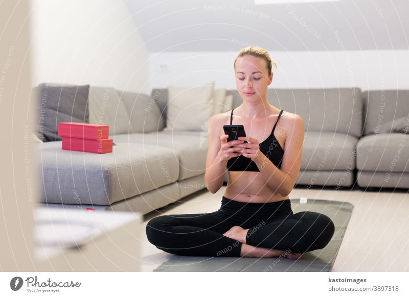 Beautiful blonde woman doing home workout indoors. Woman practice yoga at home. Fit girl using workout tutorials for healthy active lifestyle. Woman using quarantine for home workouts.