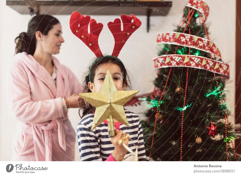 Mother and daughter in dressing gown and pajamas place Christmas decorations in realistic scene christmas tree children placing parties star illusion winter