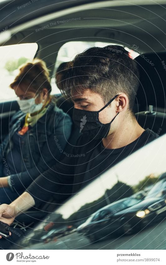 Man and woman sitting in a car using smartphones wearing the face masks to avoid virus infection caucasian covid-19 lifestyle outbreak outdoors pandemic