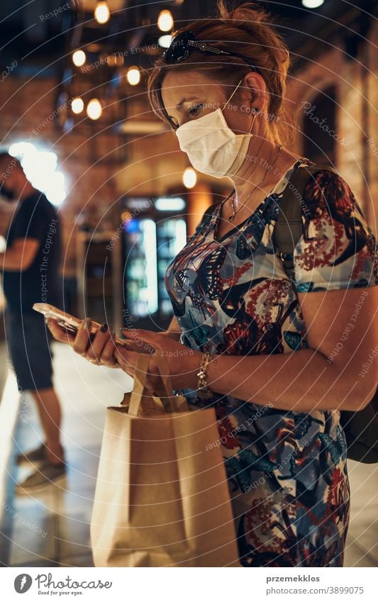 Young woman shopping in grocery store, wearing the face mask to avoid virus infection caucasian conversation covid-19 lifestyle outbreak outdoors pandemic