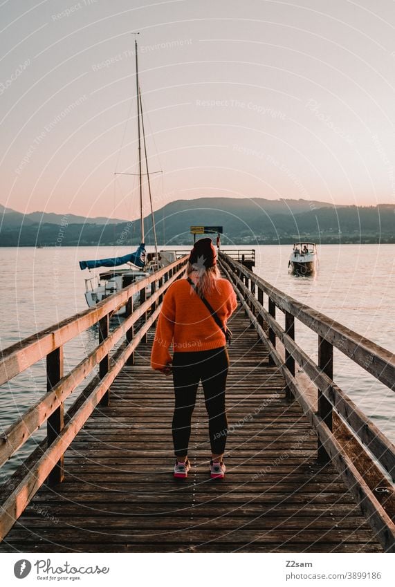 Young woman in the evening sun at lake Attersee Lake Attersee sunset Evening Sunset Nature Dusk Landscape Idyll Austria Footbridge Lakeside Exterior shot Orange